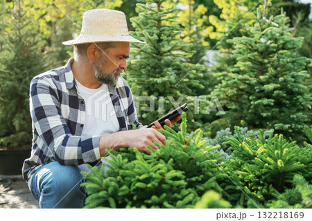 Using digital tablet, sitting. Senior gardener is at work at daytime 132218169
