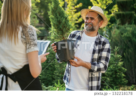 Taking a plant in a pot. Woman and man are working in the garden together with plants Taking a plant in a pot. Woman and man are working in the garden together with plants 132218178