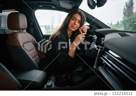 Leaning on the steering wheel. Beautiful businesswoman is in the new car 132218312