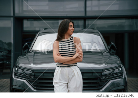 Attractive young woman is outdoors near her brand new car 132218346