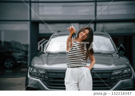 Keys for the new car. Happy owner. Attractive young woman is outdoors near her brand new car 132218347