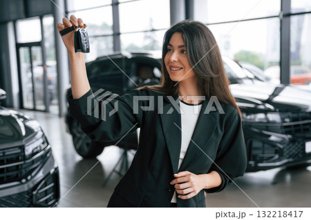 Consultant is with keys. Saleswoman in car showroom, selling automobile Consultant is with keys. Saleswoman in car showroom, selling automobile 132218417