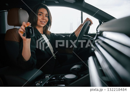 Black colored keys of new automobile. Beautiful businesswoman is in the new car Black colored keys of new automobile. Beautiful businesswoman is in the new car 132218484