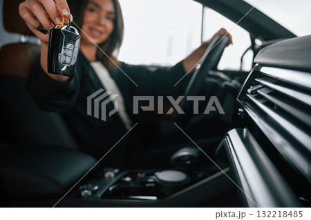 Black colored keys of new automobile. Beautiful businesswoman is in the new car Black colored keys of new automobile. Beautiful businesswoman is in the new car 132218485