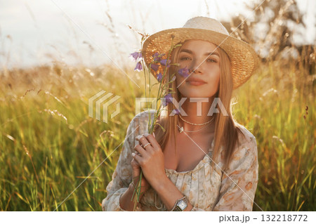 Holding plant and smiling. Beautiful young woman is on the field, countryside 132218772