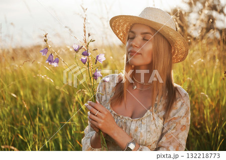 Holding plant and smiling. Beautiful young woman is on the field, countryside Holding plant and smiling. Beautiful young woman is on the field, countryside 132218773
