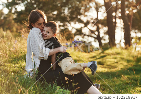 Kid gave woman a little flowers. Mother and son are in the forest together 132218917