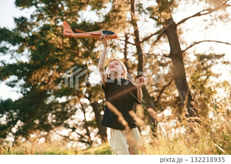 Holding red toy plane, playing. Little boy is having fun outdoors at summertime 132218935