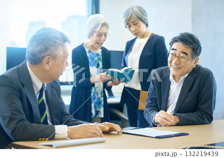 オフィスで和やかに話し合うシニアのビジネスチーム オフィスで和やかに話し合うシニアのビジネスチーム 132219439