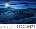countryside mountain landscape in autumn at night. rural field on hills. beautiful scenery with grassy meadows and forested slopes in highland under blue sky. scenic view in full moon light 132219474
