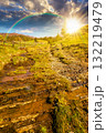 rural scene of mountain landscape in spring at sunset. green countryside with forested hills in evening light. beautiful valley sustainable development under rainbow 132219479