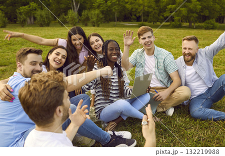 Happy college friends sitting in park, using laptop, laughing and having fun together Happy college friends sitting in park, using laptop, laughing and having fun together 132219988