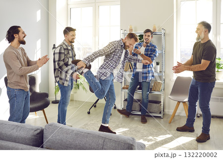 Happy man dancing while his cheerful friends are standing around and clapping hands Happy man dancing while his cheerful friends are standing around and clapping hands 132220002
