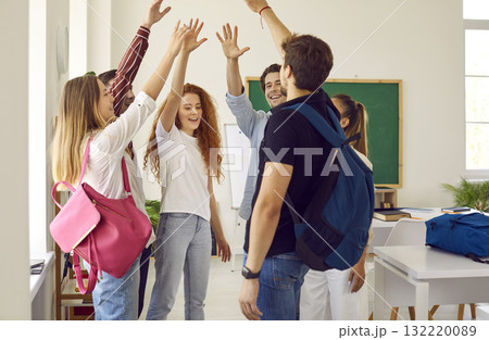 Team of happy students standing in the school classroom and giving each other a high five 132220089