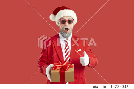Portrait of funny surprised man who holds Christmas present in his hand and who shows thumb up. Portrait of funny surprised man who holds Christmas present in his hand and who shows thumb up. 132220329