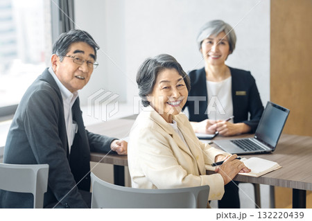 会議室で笑顔を見せるシニアのビジネスマンと顧客 132220439