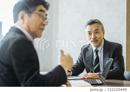 会議で相手の話を聞く笑顔のシニアビジネスマン 132220440