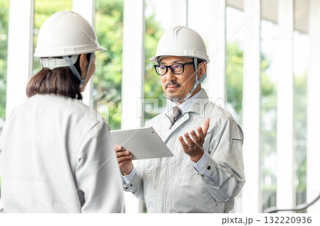 タブレットを見て打ち合わせをする 132220936