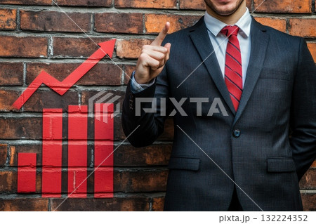 Businessman in Suit Pointing at Bar Graph Against Brick Wall Background for Financial Growth Businessman in Suit Pointing at Bar Graph Against Brick Wall Background for Financial Growth 132224352
