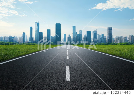 Expansive Road Leading to Modern City Skyline Under Bright Blue Sky and Green Grass Expansive Road Leading to Modern City Skyline Under Bright Blue Sky and Green Grass 132224446