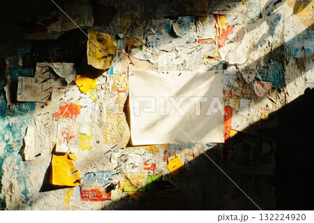 Captivating Urban Texture with Colorful Layers of Torn Paper on Wall Illuminated by Sunlight, Empty White Space Ready for Your Creative Touch 132224920