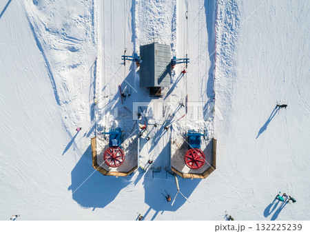 Skiers and snowboarders preparing to ascend the slopes at a winter resort in a snow-covered landscape during a sunny day. Skiers and snowboarders preparing to ascend the slopes at a winter resort in a snow-covered landscape during a sunny day. 132225239