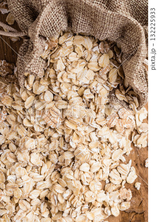 oat flakes cereal in burlap sack on wooden table. oat flakes cereal in burlap sack on wooden table. 132225933