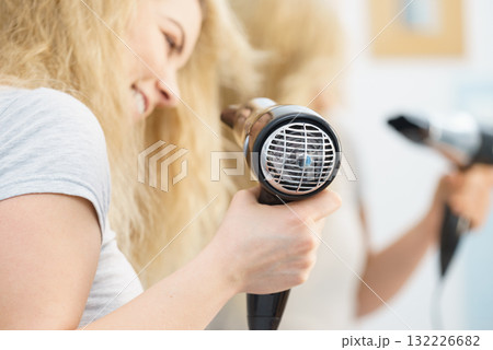 Blonde woman using hair dryer 132226682