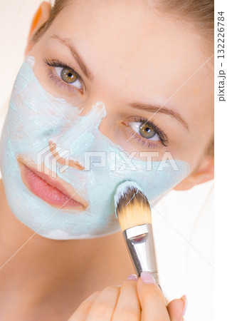 Girl apply green mud mask to face Girl apply green mud mask to face 132226784