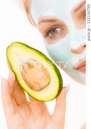Girl facial mud mask holds avocado fruit 132226789