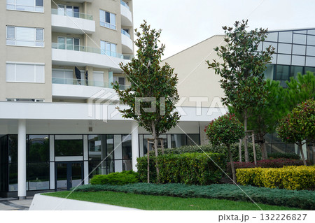 A modern residential building with landscaped greenery and well-maintained trees in front 132226827