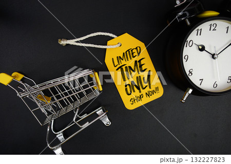 Mini Trolley Shopping Cart and price tag with message "Limited Time Only Shop Now" and alarm clock on black background 132227823