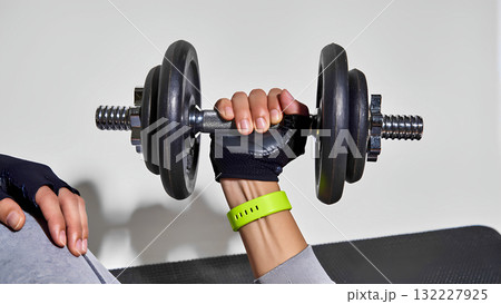 Close-up of a gloved hand holding a dumbbell. Strength training at the gym. Close-up of a gloved hand holding a dumbbell. Strength training at the gym. 132227925