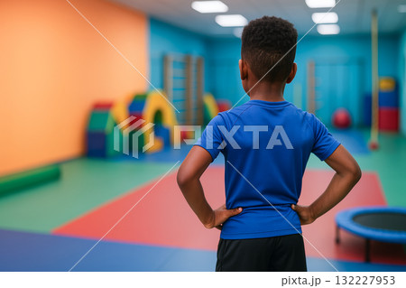 Young african american boy showing determination while standing in a colorful gymnasium. concept of youthful resolve, physical fitness, indoor activity, childhood confidence, copy space 132227953