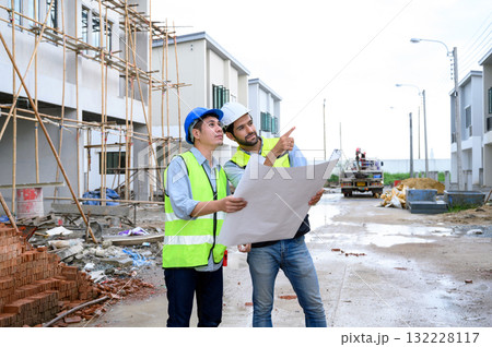Construction engineer and architect check plan working with the blueprint on construction site. They are in safety vests with helmets for safety. Construction project concept. Construction engineer and architect check plan working with the blueprint on construction site. They are in safety vests with helmets for safety. Construction project concept. 132228117