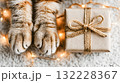 Cat paws beside wrapped gift with fairy lights on soft surface 132228367