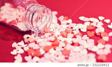 小瓶から零れるハート型のトッピングシュガー　かわいい背景装飾　溢れる気持ち　製菓材料 132228411
