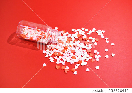 小瓶から零れるハート型のトッピングシュガー　かわいい背景装飾　溢れる気持ち　製菓材料 132228412