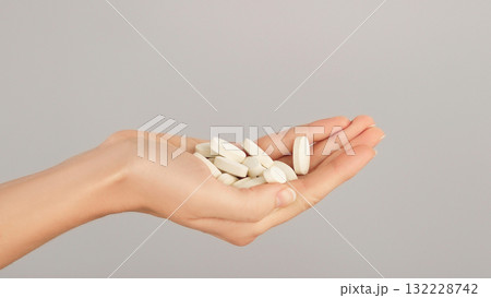 A close-up of a hand full of white pills. Conceptual ideas for vitamins, bone and joint supplements, medications, and daily self-care. A close-up of a hand full of white pills. Conceptual ideas for vitamins, bone and joint supplements, medications, and daily self-care. 132228742