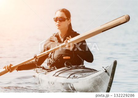 Kayaking Woman Paddle Ocean - Woman kayaking in ocean with paddle on a sunny day. 132229286