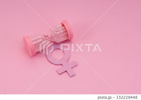 Hourglass with the female gender symbol. Women's health, menopause concept. 132229448