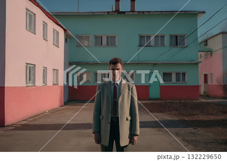 Portrait of a man standing in a courtyard between buildings in a small suburb Portrait of a man standing in a courtyard between buildings in a small suburb 132229650