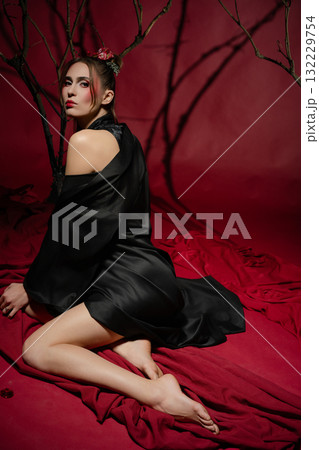 Woman in traditional Japanese dress poses elegantly in a studio with red backdrop Woman in traditional Japanese dress poses elegantly in a studio with red backdrop 132229754