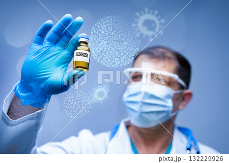 Scientist examining a vaccine vial in a laboratory setting for COVID-19 research 132229926