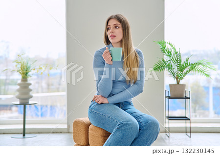 Portrait of relaxed beautiful young woman sitting at home on chair with cup Portrait of relaxed beautiful young woman sitting at home on chair with cup 132230145