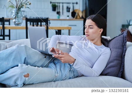 Young teenage girl using laptop for video chat lying on sofa at home Young teenage girl using laptop for video chat lying on sofa at home 132230181
