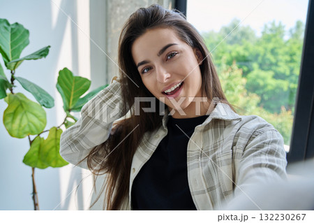 Close-up selfie portrait of teenage female looking at web camera 132230267