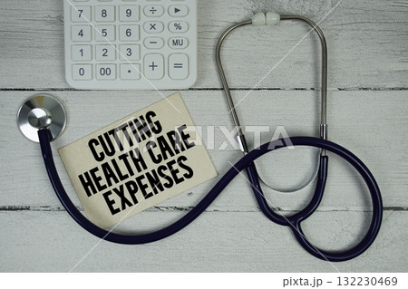 Cutting Health Care Expenses text with Stethoscope and calculator on wooden background 132230469