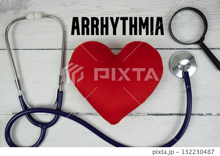 Arrhythmia text with Red heart, Magnifying glass and Medical Stethoscope on wooden background 132230487