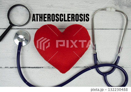 Atherosclerosis text with Red heart, Magnifying glass and Medical Stethoscope on wooden background 132230488